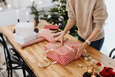 Person verpackt entspannt Geschenke am Tisch zu Hause