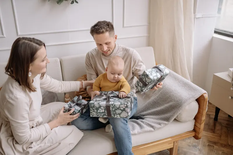 Familie packt Weihnachtsgeschenke gemeinsam im Wohnzimmer aus