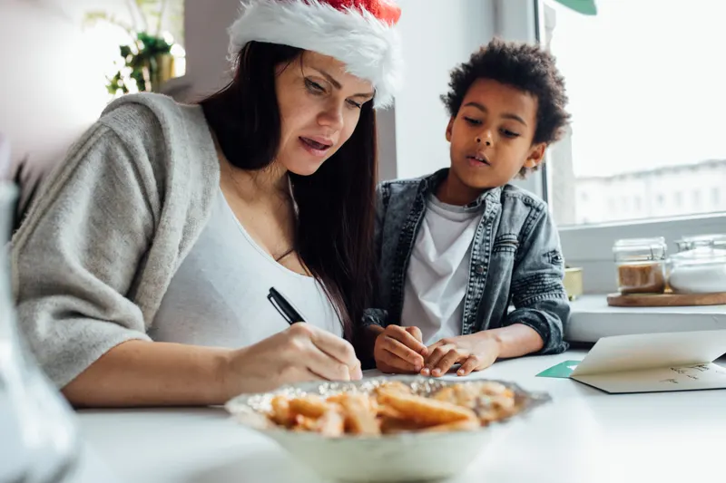 Elternteil und Kind schreiben gemeinsam Weihnachtswünsche auf Elternteil und Kind schreiben gemeinsam Weihnachtswünsche auf
