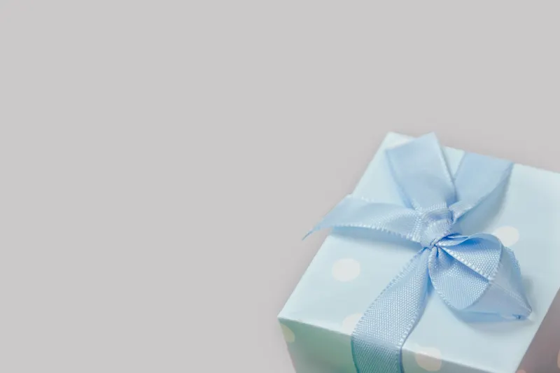 Person verpackt ein Geschenk zur Taufe mit Geschenkpapier Person verpackt ein Geschenk zur Taufe mit Geschenkpapier
