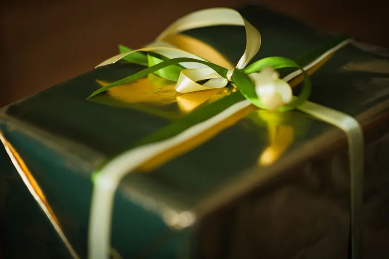 Person verpackt ein Geburtstagsgeschenk mit Geschenkpapier Person verpackt ein Geburtstagsgeschenk mit Geschenkpapier