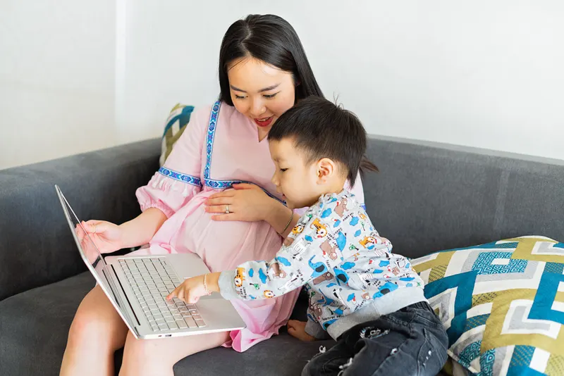 Eltern und Kind stellen gemeinsam eine Kommunion-Wunschliste am Laptop zusammen