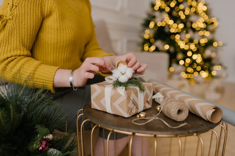 Person verpackt ein Weihnachtsgeschenk mit Geschenkpapier Person verpackt ein Weihnachtsgeschenk mit Geschenkpapier