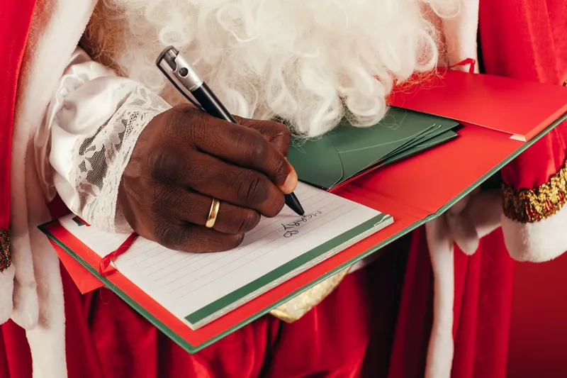 Person notiert Weihnachtswünsche für eine digitale Wunschliste Person notiert Weihnachtswünsche für eine digitale Wunschliste