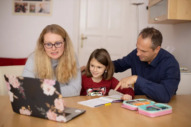 Eltern und Kind stellen gemeinsam eine Einschulungs-Wunschliste am Laptop zusammen Eltern und Kind stellen gemeinsam eine Einschulungs-Wunschliste am Laptop zusammen